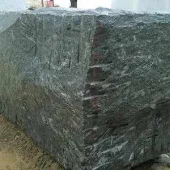 Rough-cut granite block displayed in a collection of natural stone materials.