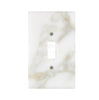 The Calacatta Gold Marble Single TOGGLE Plate Switch Wall Plate from SurfacesGalore features a white marble design with beige veins and a central rectangular opening. Each piece showcases natural stone variations, offering a truly unique aesthetic. Perfect for anyone in search of luxury switch plate covers that add an elegant touch to any room.