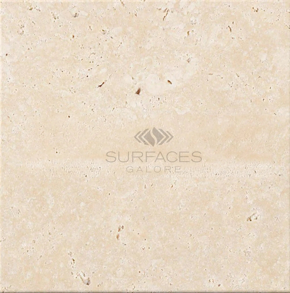 An Ivory (Light) Travertine 4X4 (Cross-Cut) Tumbled tile from SurfacesGalore, elegantly inscribed at the center, offers a touch of sophistication that complements the look of Premium Light Travertine.