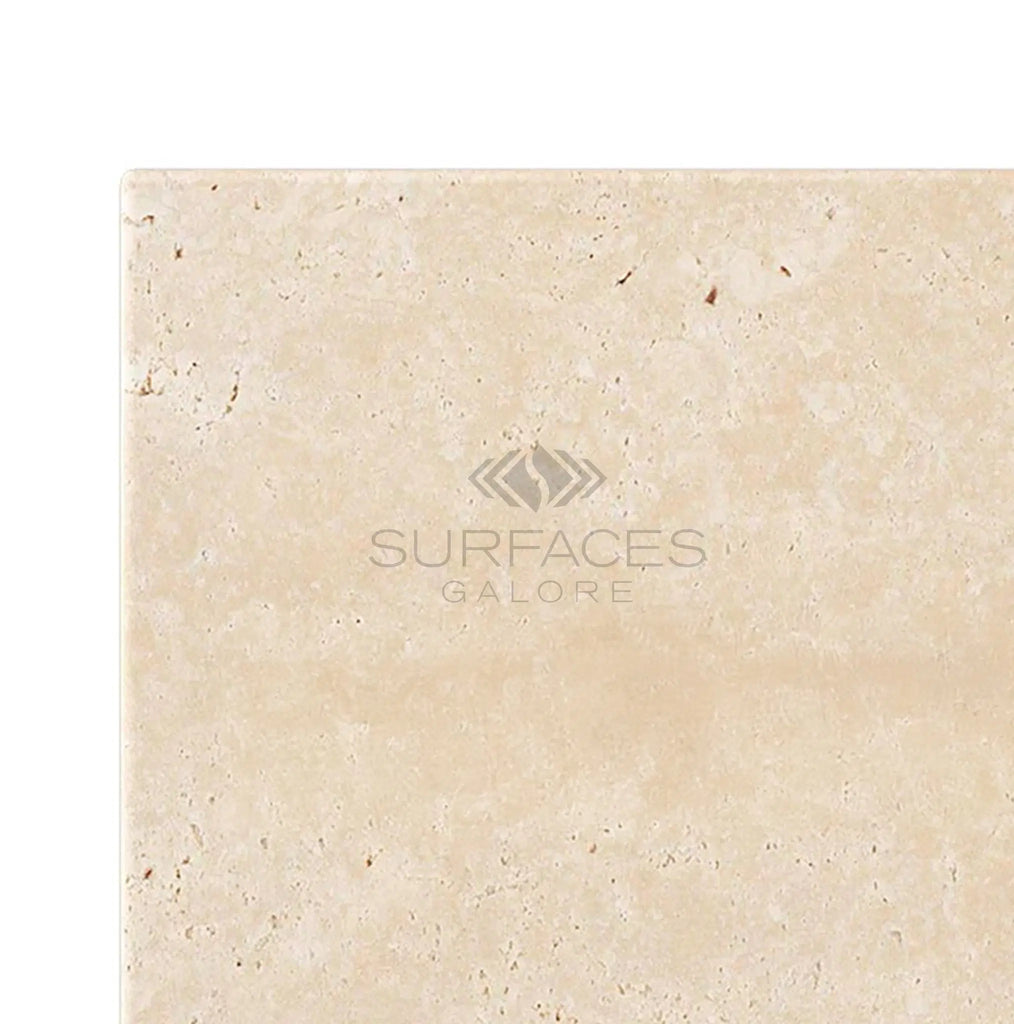 An Ivory (Light) Travertine 4x4 (Cross-Cut) Tumbled tile with "SurfacesGalore" and a logo engraved on it.