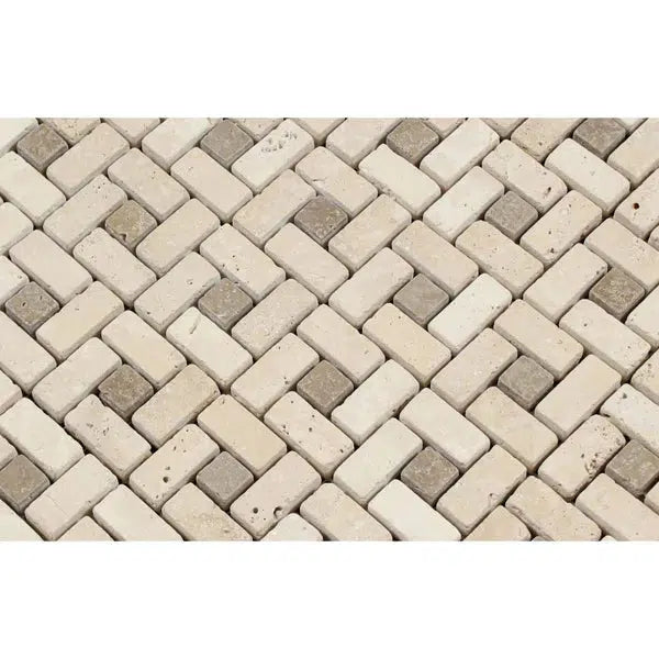 A close-up of a mosaic tile pattern composed of rectangular pieces arranged in a herringbone design. The tiles, in various shades of beige, cream, and light travertine, create a visually appealing and textured surface. Discover more designs like the Ivory (Light) Travertine 5/8X1 1/4 Pinwheel (MINI) w/ Noce Dots Mosaic Tumbled at SurfacesGalore.