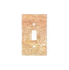 The Scabos Travertine Single TOGGLE Wall Plate by SurfacesGalore is a luxury home decor item that features a reddish-brown, golden, and beige textured finish on a white background.