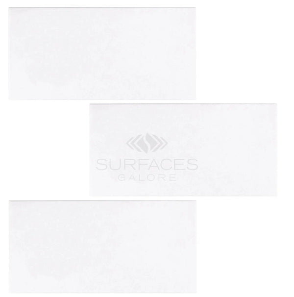 Three large rectangular white tiles, crafted from Thassos White (Greek) 12X24 Marble Polished-Honed, are arranged in a staggered pattern on a blank background, with the text "SurfacesGalore.