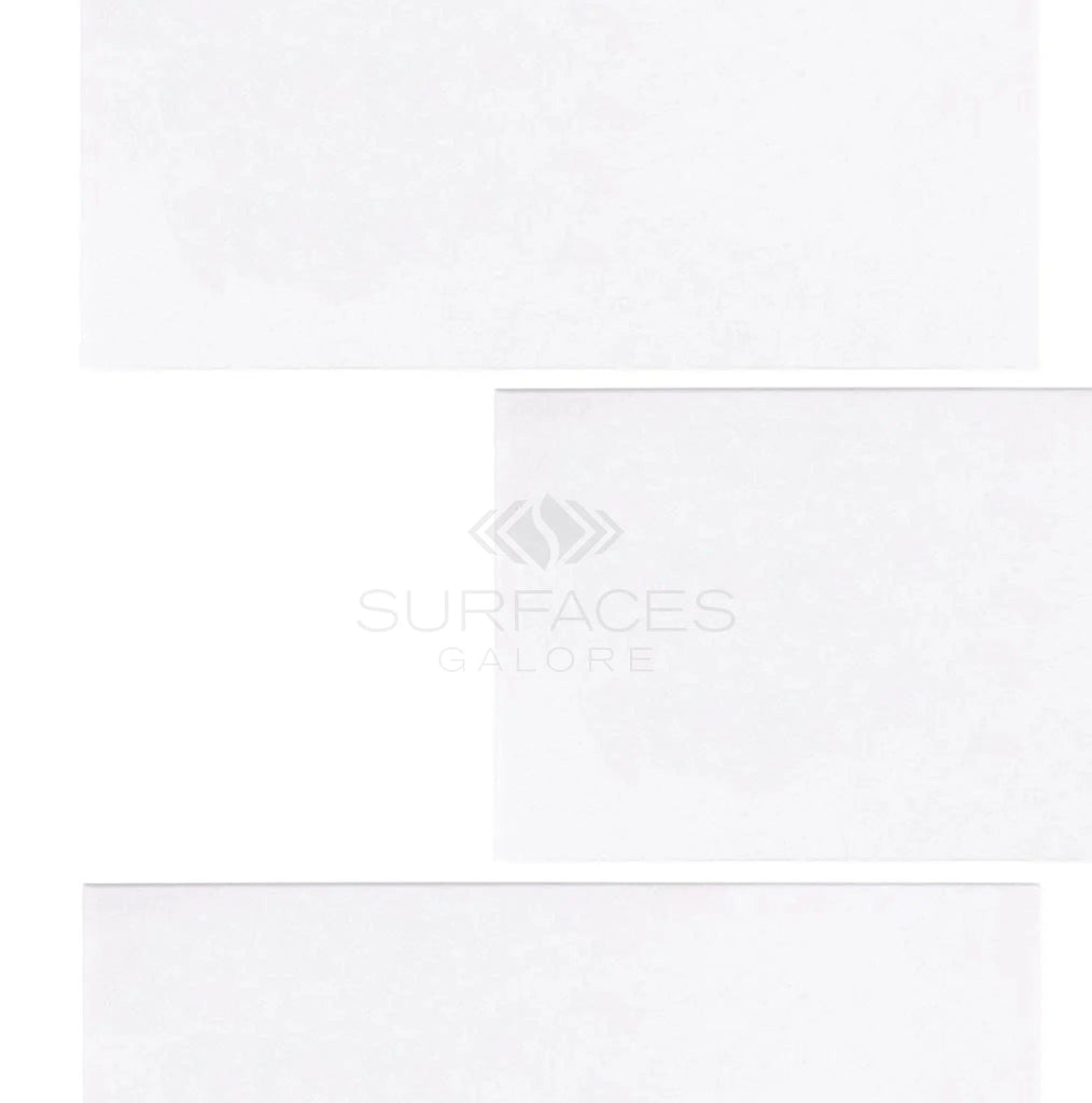 Three 12x24 Thassos White (Greek) Marble Polished-Honed tiles are arranged vertically, with the text "SurfacesGalore" elegantly centered in the middle.