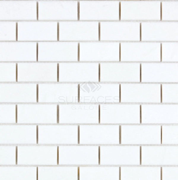 Thassos White (Greek) 1X2 Brick Mosaic Marble Polished-Honed tiles in a white rectangular pattern with thin grout lines, creating a subtle shadow effect and featuring the text "SurfacesGalore," reminiscent of pure white marble.