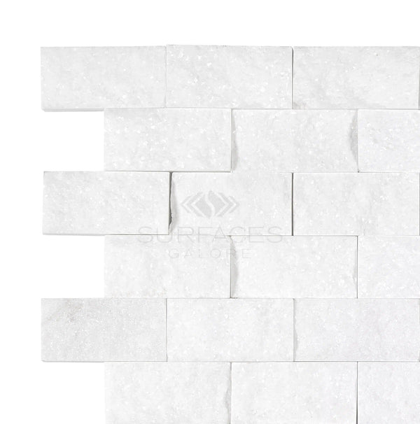 A close-up of a white textured tile wall, featuring SurfacesGalore's Thassos White (Greek) 1X2 Brick Mosaic Marble Split-Faced arranged in a staggered brick-like pattern.