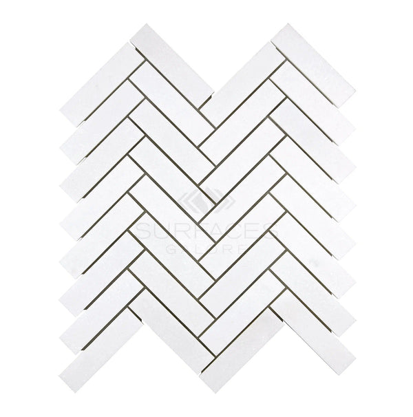 A display of the Thassos White (Greek) 1X4 Herringbone Mosaic Marble Polished-Honed from SurfacesGalore, set against a plain background, highlights its pure white color.