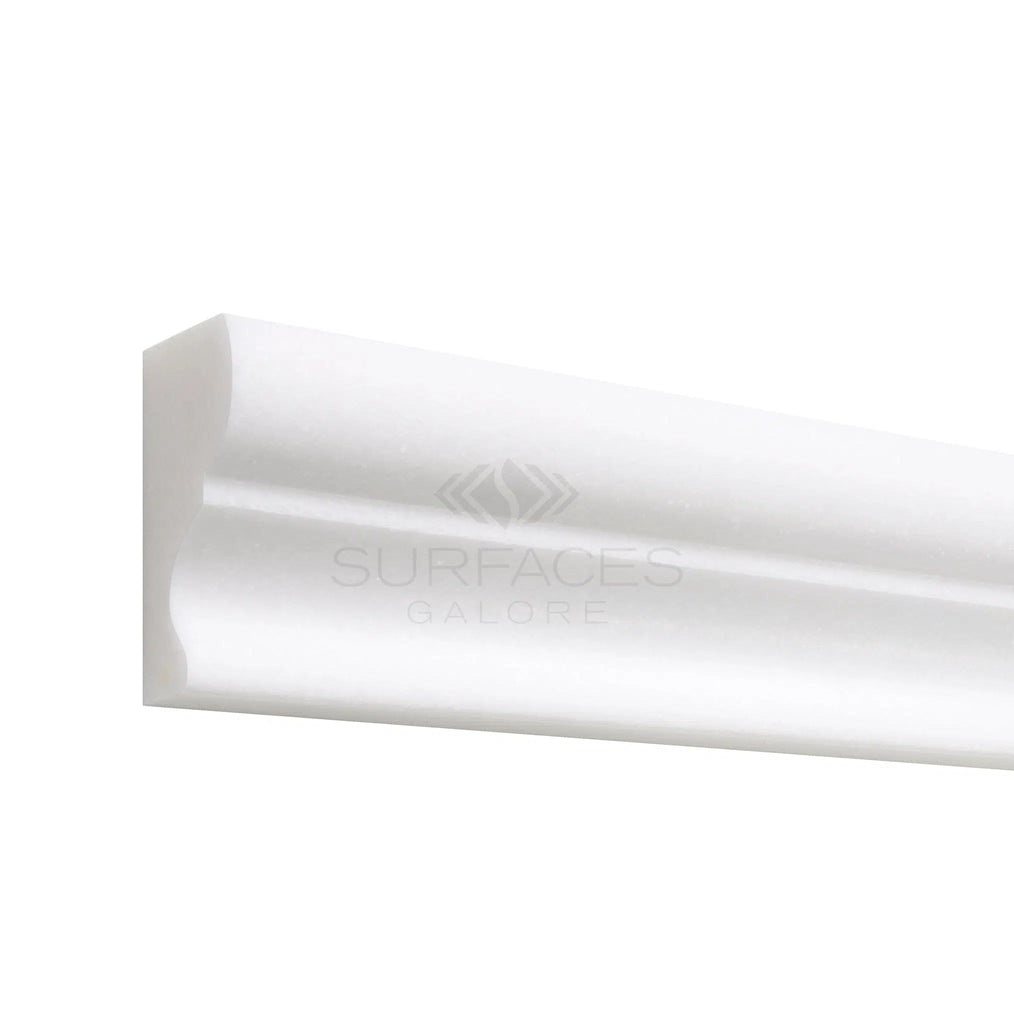 Thassos White (Greek) 2x12 Crown (Mercer) Molding Marble Polished-Honed, branded as SurfacesGalore, features a pure white color that ensures versatile applications. The image depicts a close-up of one end highlighting its decorative edge.