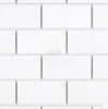 The Thassos White (Greek) 2X4 Straight-Edged Brick Mosaic Marble Polished-Honed tiles, emblazoned with the SurfacesGalore logo, feature a sleek arrangement in a classic brick pattern. These sophisticated tiles capture the luxurious essence of Thassos White Marble, reflecting the enduring elegance of Greek marble aesthetics.