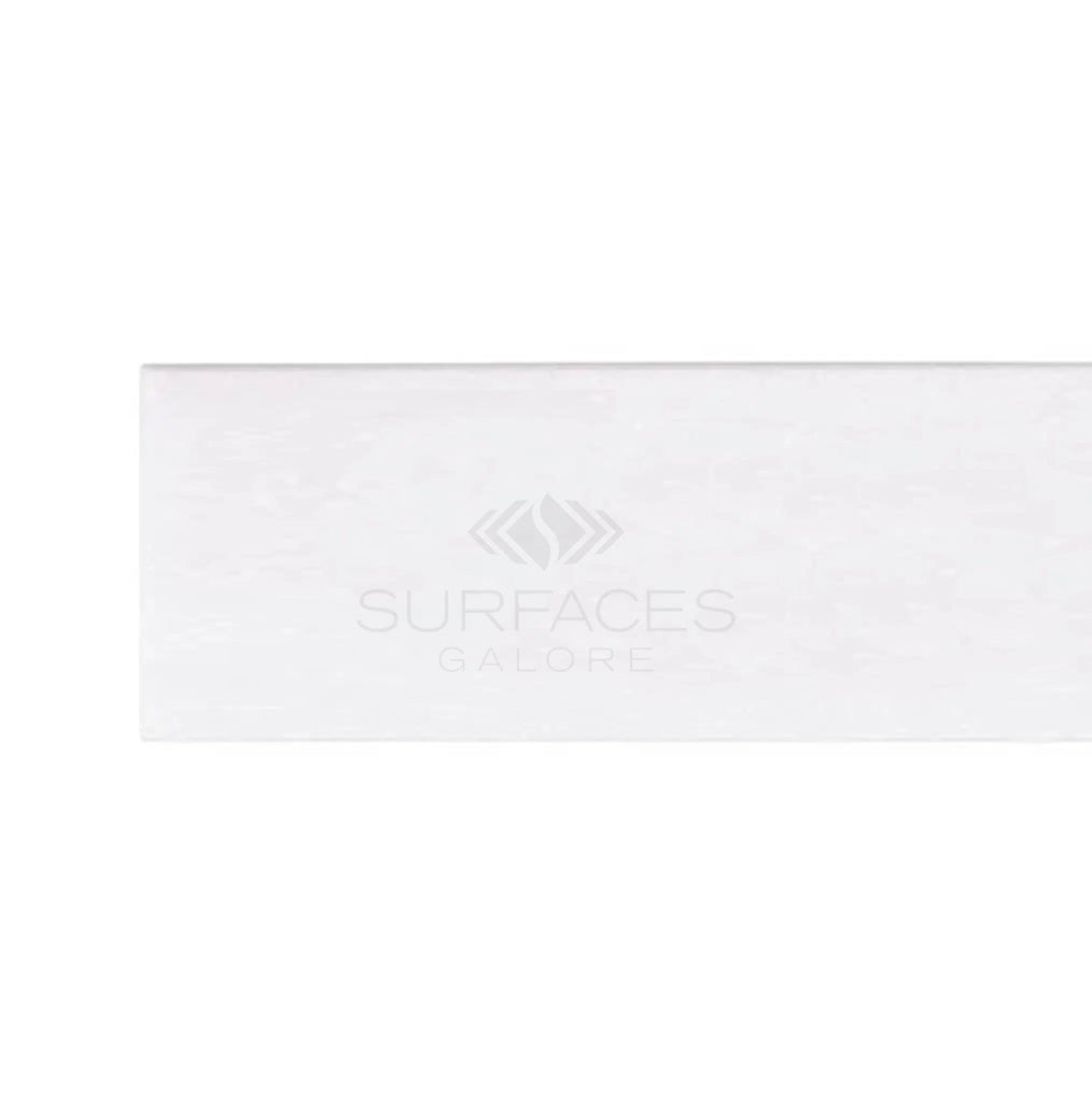 Rectangular tile sample named "Thassos White (Greek) 2X8 Marble Polished-Honed," featuring a subtle glossy finish that exudes luxury and proudly displaying the SurfacesGalore logo in the center.