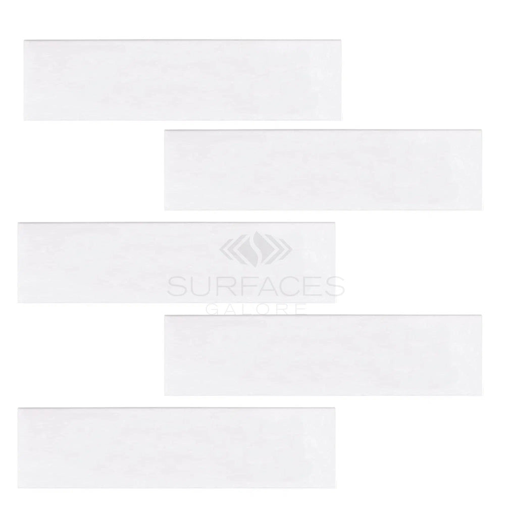 Five staggered Thassos White (Greek) 2X8 Marble Polished-Honed tiles arranged diagonally on a plain background. The faintly visible "SurfacesGalore" brand adds to the luxurious look.