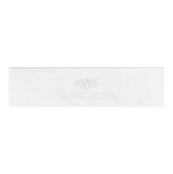 A rectangular white tile with a subtle surface texture, bearing the "SurfacesGalore" brand in the center and exuding a luxurious look reminiscent of Thassos White Marble, known as the Thassos White (Greek) 2X8 Marble Polished-Honed.