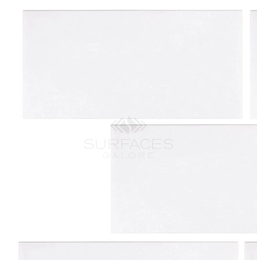 White rectangular tiles with subtle, crystalline textures, arranged closely. The faint "SurfacesGalore" logo overlays neatly, echoing the elegance of Thassos White (Greek) 3X6 Marble Polished-Honed.