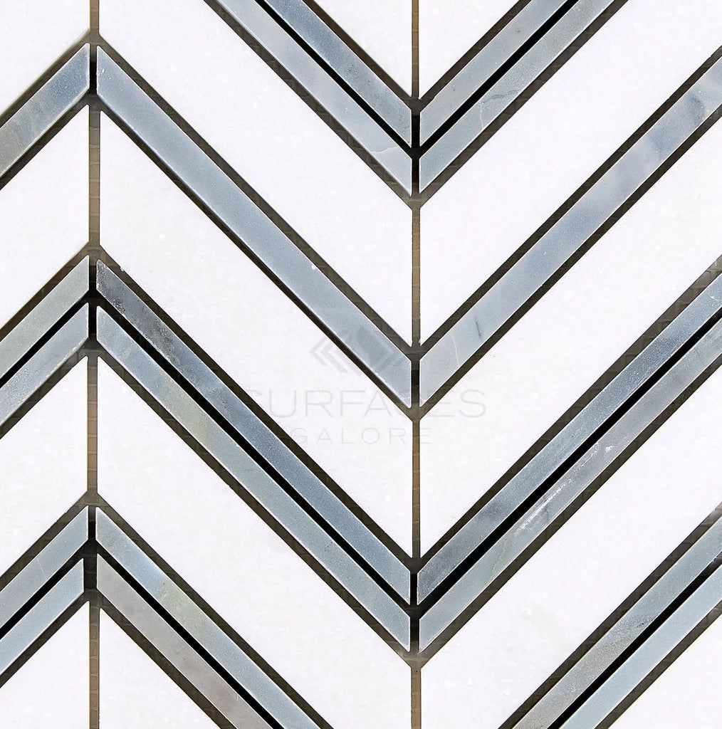 Experience the timeless elegance of the Thassos White (Greek) Large Chevron (w/ Blue-Gray) Mosaic Marble Polished-Honed, featuring a sophisticated white and gray chevron pattern. Crafted from high-quality Thassos White Marble, this stunning mosaic creates a symmetrical, zigzag design ideal for creating elegant interiors. Available exclusively at SurfacesGalore.