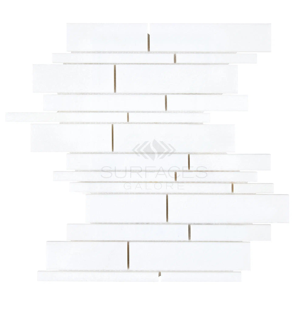 White rectilinear tiles of differing lengths are arranged in a staggered pattern, creating a vertically aligned mosaic akin to the Thassos White (Greek) Manhattan (Random-Strip) Mosaic Marble Polished-Honed from SurfacesGalore.