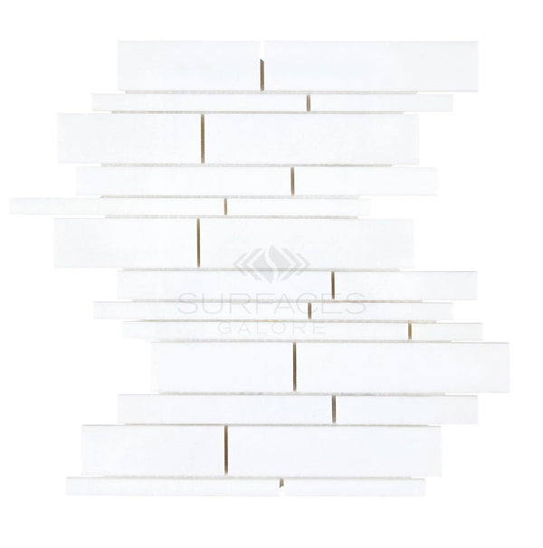 White rectilinear tiles of differing lengths are arranged in a staggered pattern, creating a vertically aligned mosaic akin to the Thassos White (Greek) Manhattan (Random-Strip) Mosaic Marble Polished-Honed from SurfacesGalore.