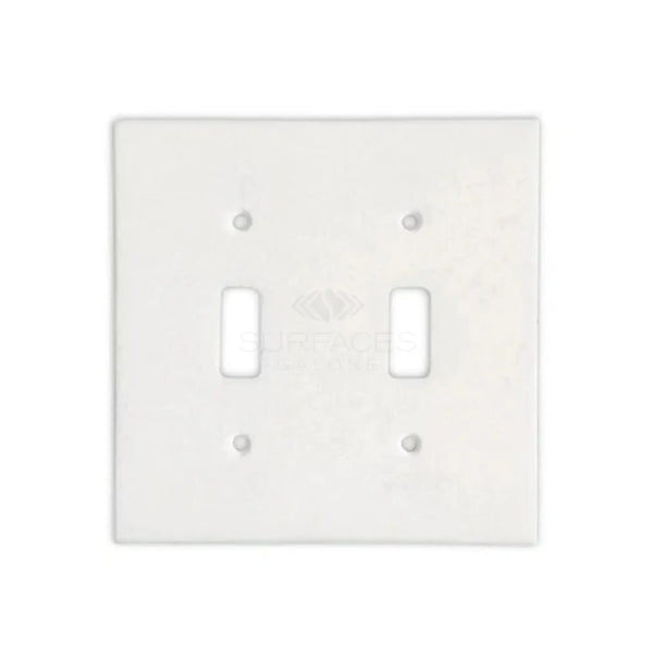 A luxurious home decor piece, the Thassos White Marble Double TOGGLE Switch Wall Plate from SurfacesGalore features two rectangular openings for switches, blending seamlessly into a pristine white background.