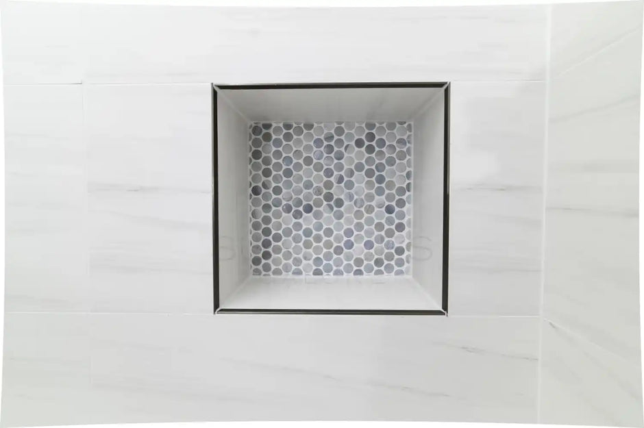 Square niche with hexagonal tiles, set in a shower wall with white marble-like tiles.