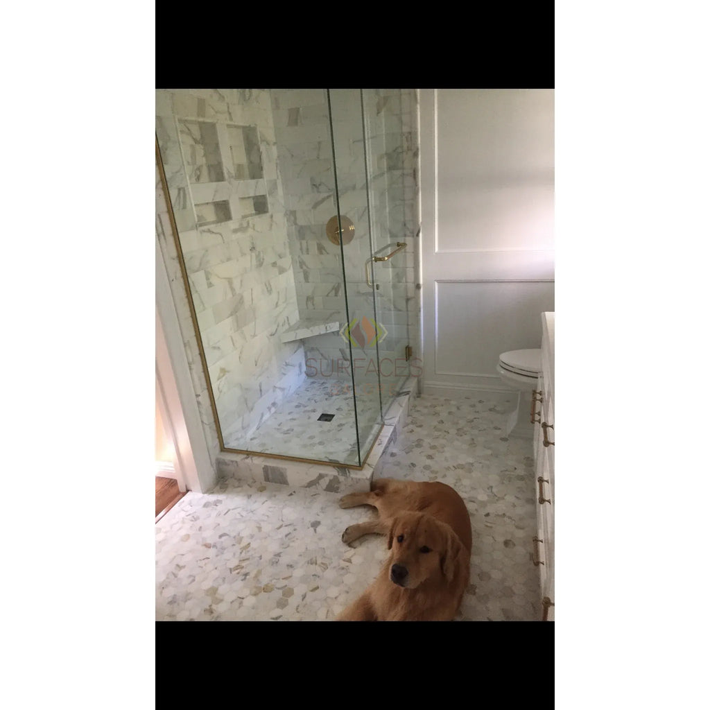 Luxurious bathroom featuring Calacatta Gold Marble Tile and a Golden Retriever