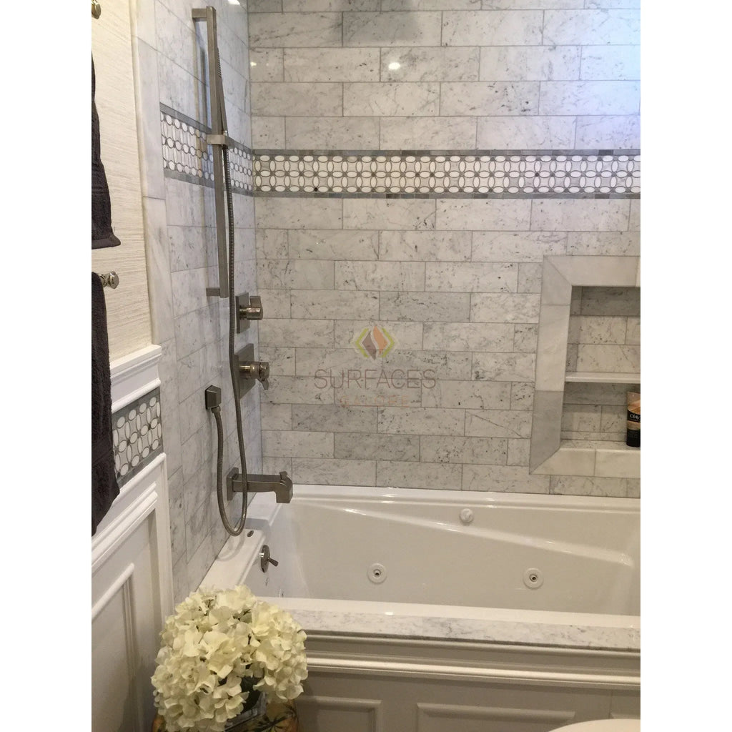 White bathtub with Carrara White marble tile surround in polished finish