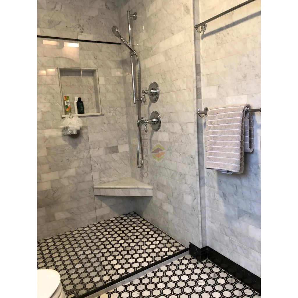 Marble-tiled shower featuring Carrara White 1X2 Brick Mosaic in hexagon-patterned floor