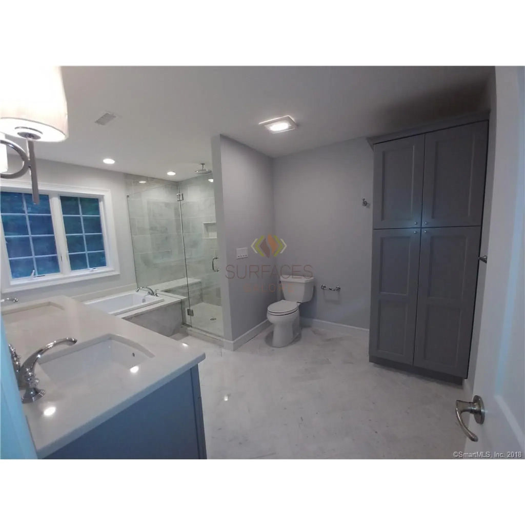 Luxurious bathroom featuring gray cabinets and Carrara White mosaic marble tile