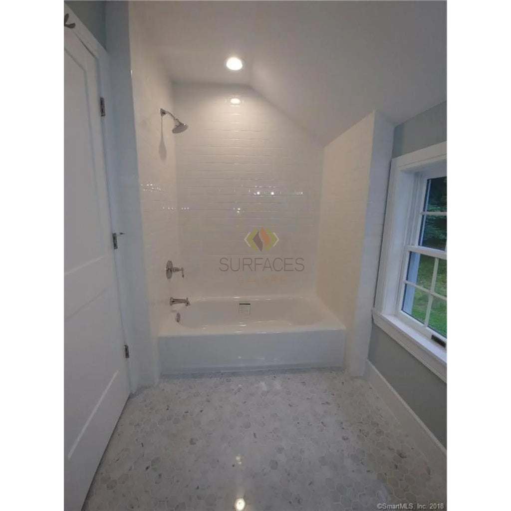 White bathtub and shower surrounded by Carrara White Greek Key Border with Black accents