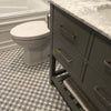 Gray bathroom vanity with marble top alongside Carrara White Herringbone Mosaic Tile