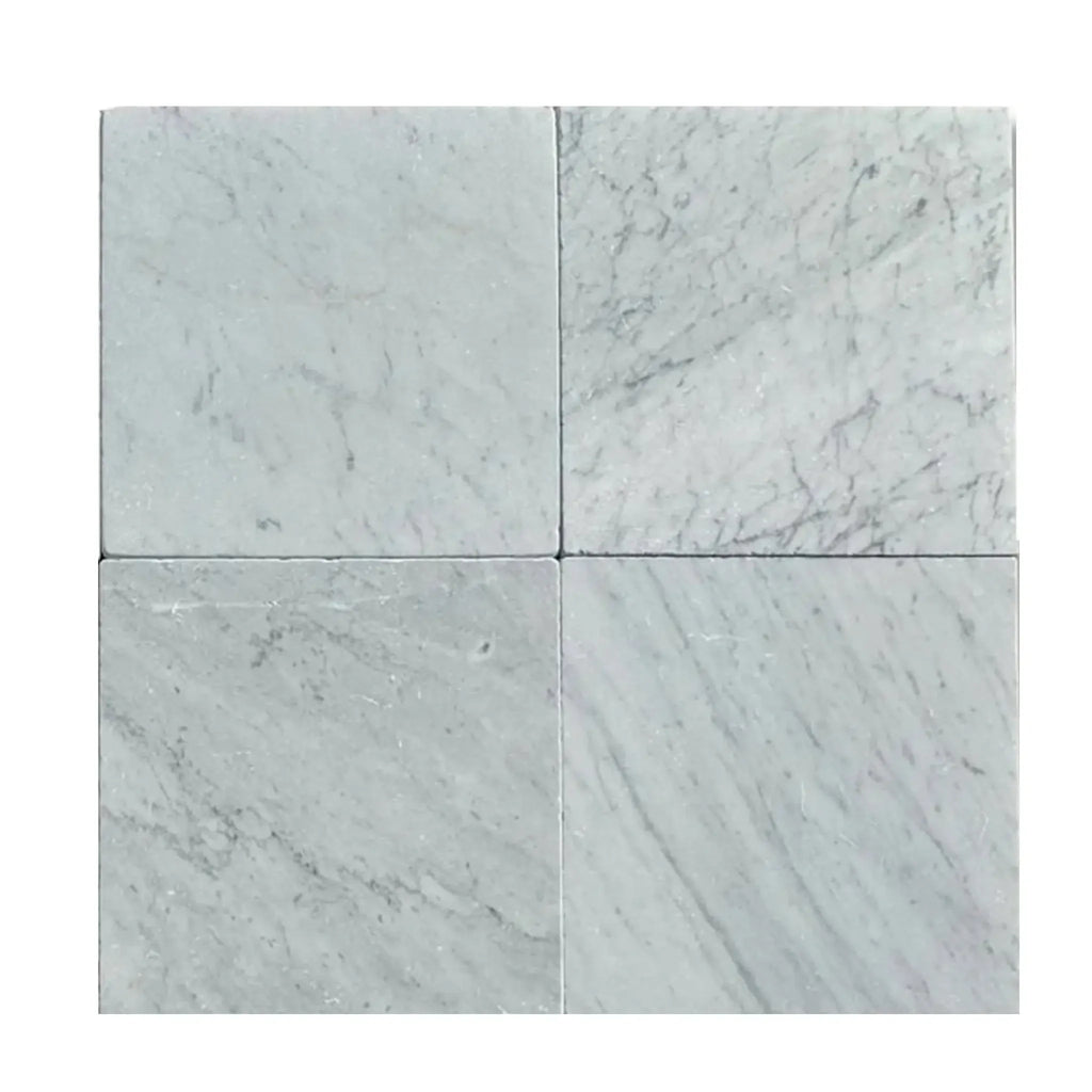 Four Carrara White Marble 12x12 Tumbled tiles displaying elegant veining and finish