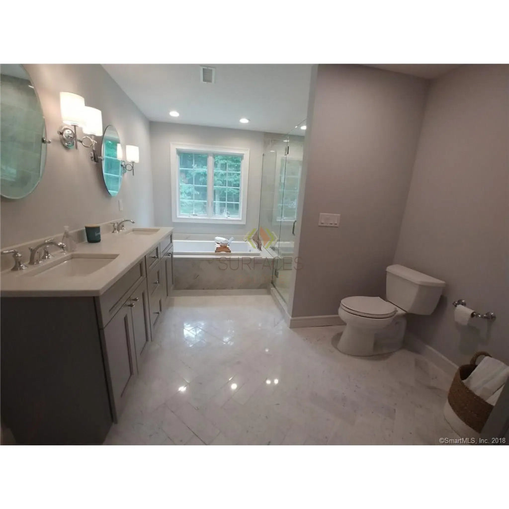 Bathroom featuring double vanity and toilet with Carrara White Penny-Round Mosaic Tile