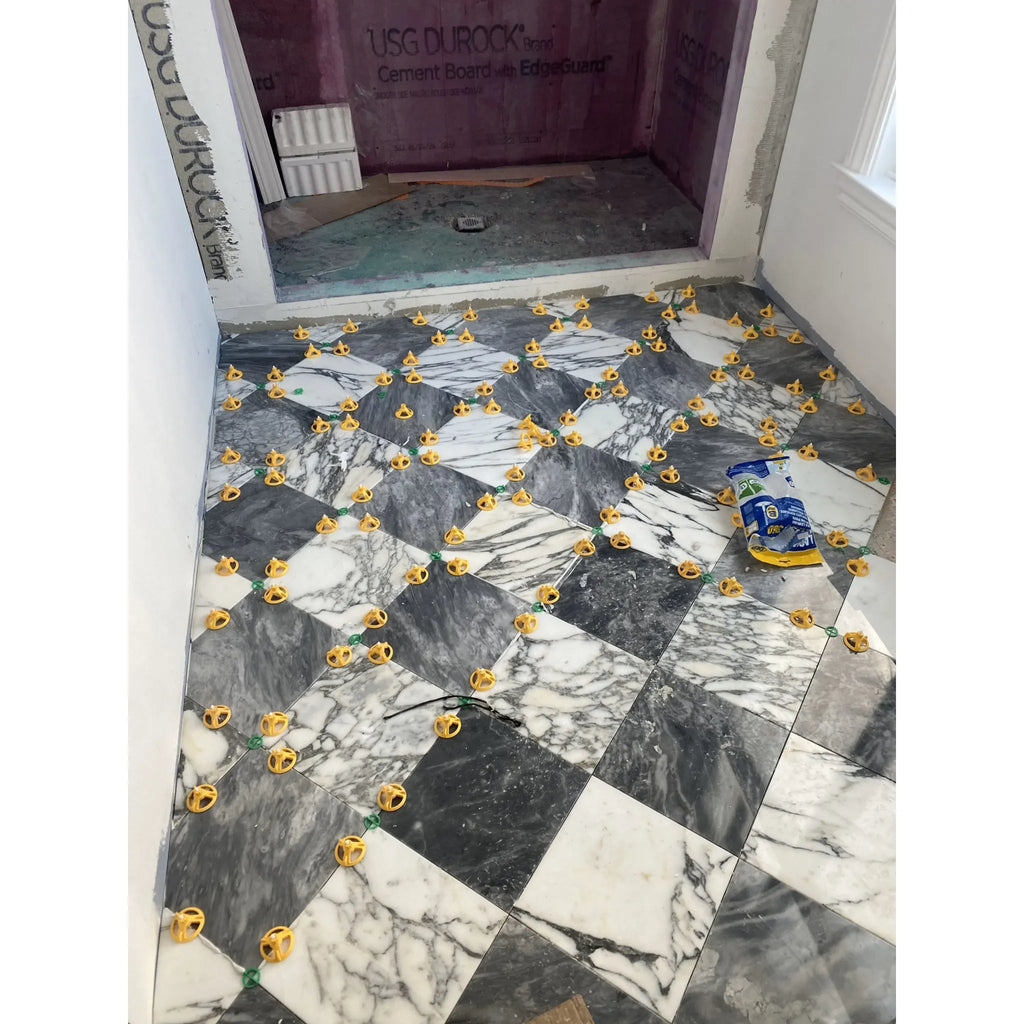 Marble tile floor featuring yellow spacers in Checkerboard Bardiglio and Calacatta Gold set