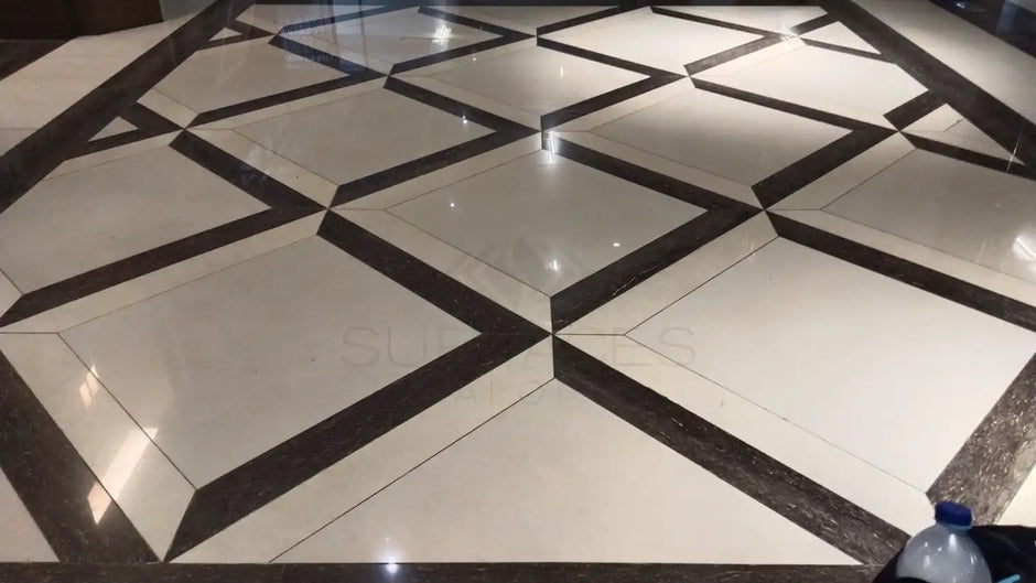 A geometric floor pattern with glossy tiles in shades of cream and dark brown. A small water bottle is in the corner.