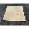 Four beige Ivory Travertine 12X12 cross-cut filled and polished tiles displayed