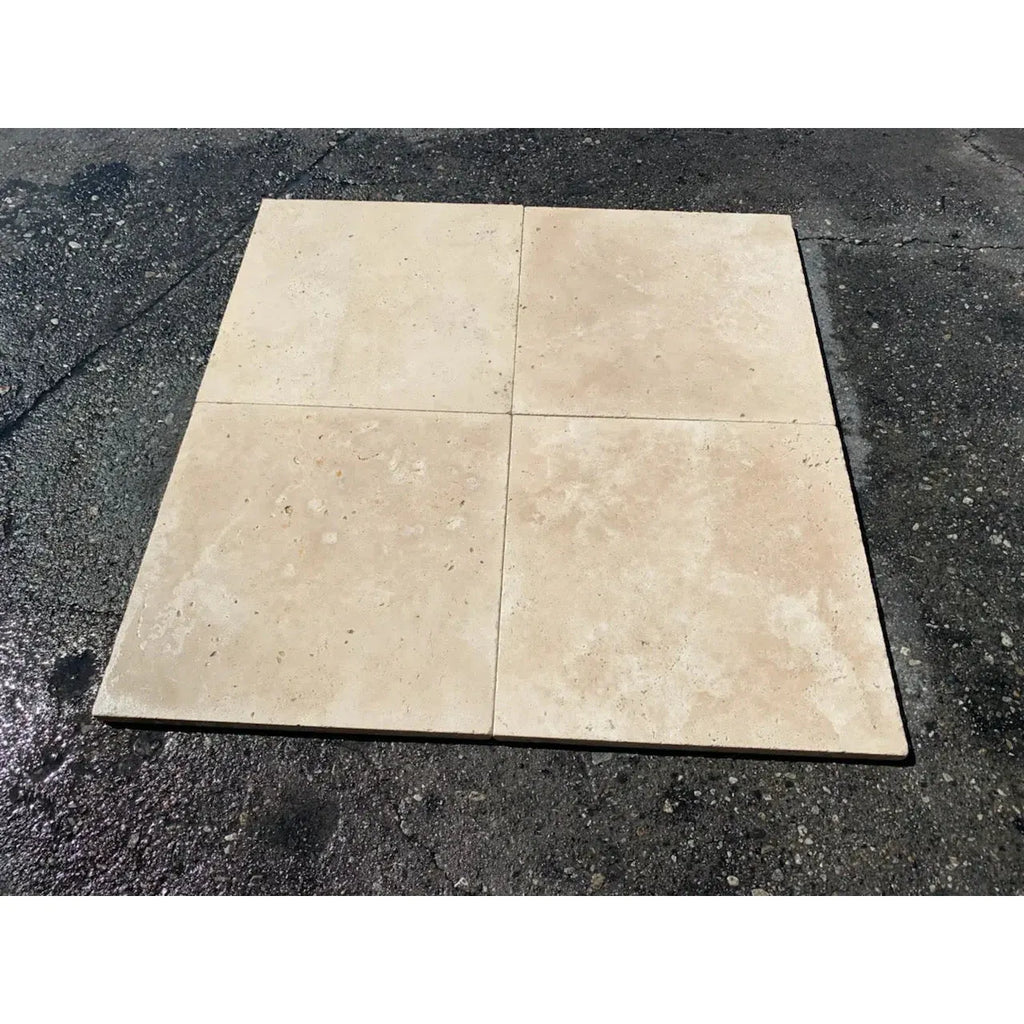 Four beige travertine tiles from the Ivory Light Travertine collection 16X16