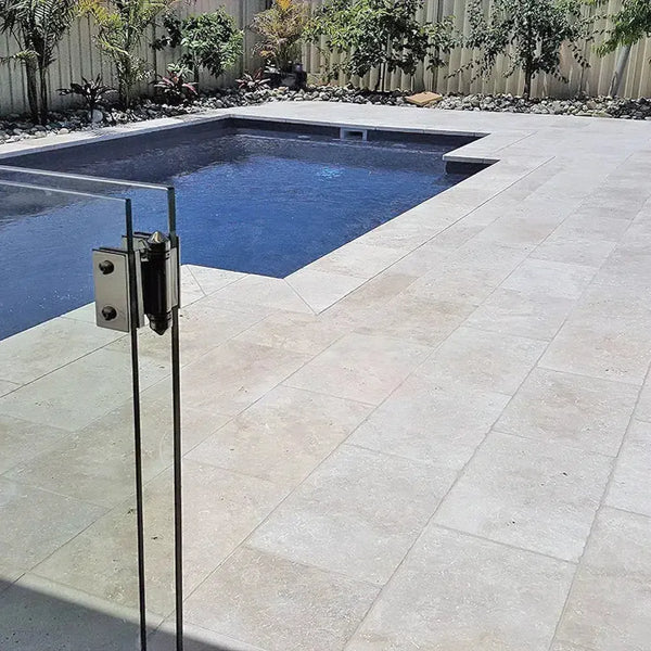 Rectangular swimming pool with glass fence and Ivory (Light) Travertine pavers