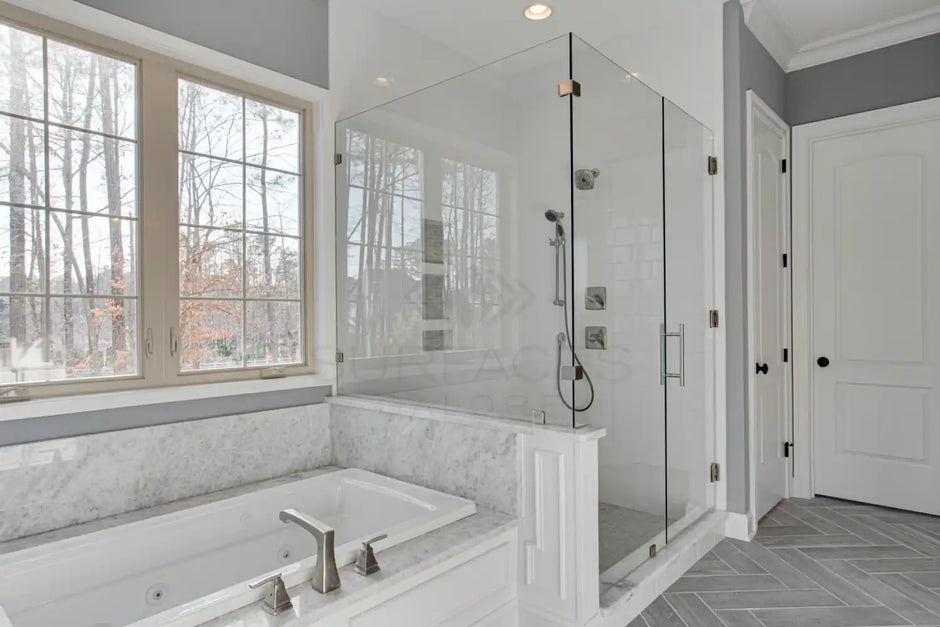 Modern bathroom with a large glass-enclosed shower, marble bathtub, and large window. Neutral colors dominate the space.