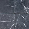 Four gray Nero Marquina marble tiles with white veining in 12X12 tumbled finish