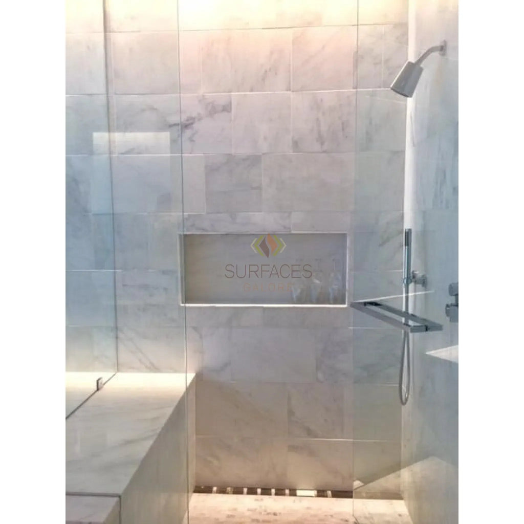 Marble-tiled shower with built-in bench featuring Oriental White Herringbone Mosaic