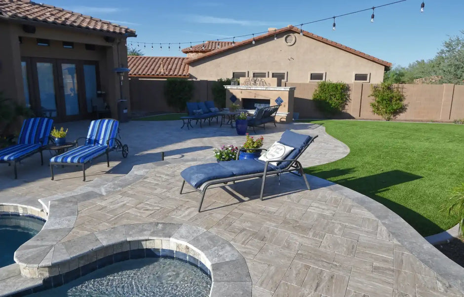 Backyard with outdoor seating, string lights, fireplace, and pool under a clear sky.