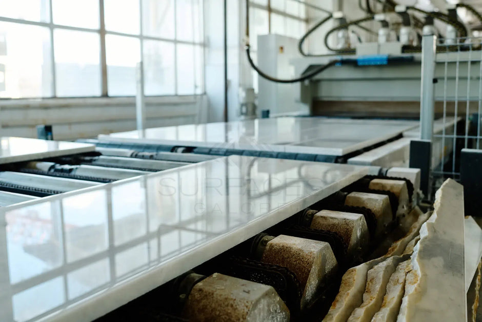 Stone slabs being polished on a conveyor belt in an industrial workshop.