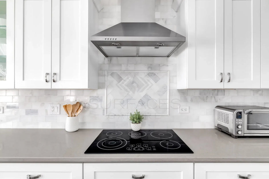 Modern kitchen with white cabinets, stainless steel range hood, electric cooktop, and toaster oven on the counter.