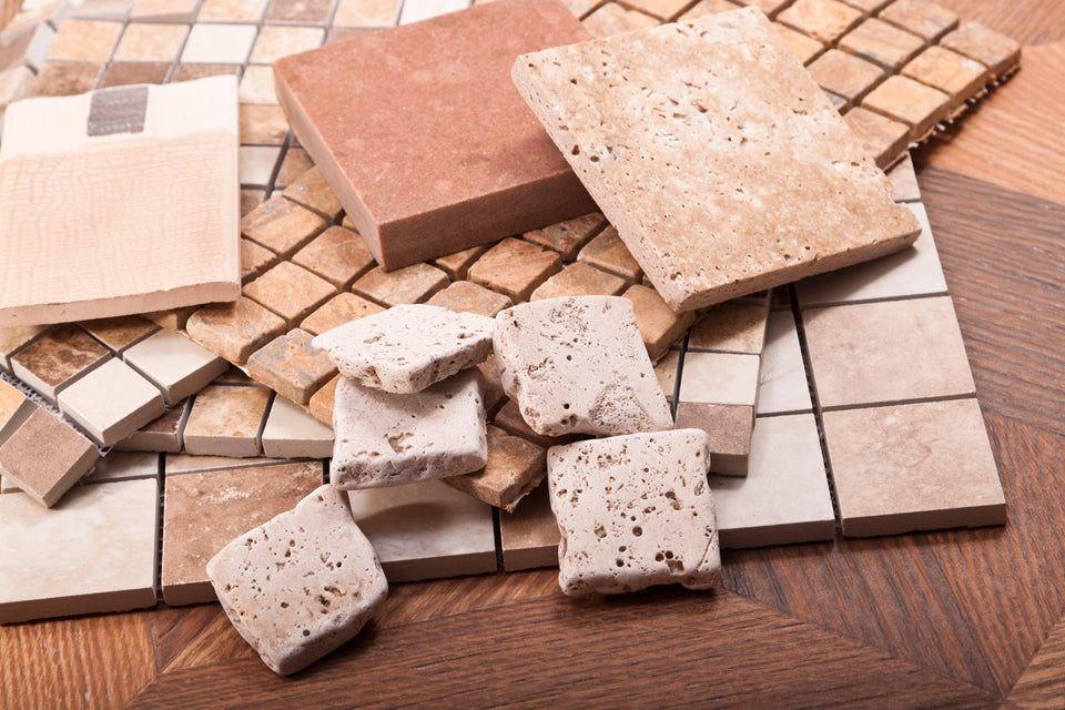 Various ceramic tiles laid out on a wooden surface, showcasing different textures, sizes, and colors.