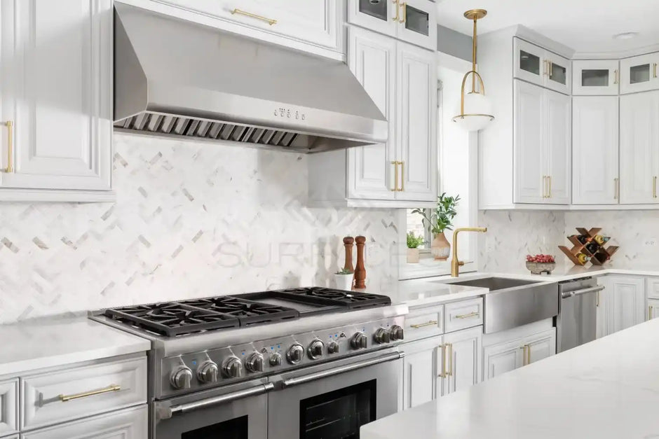 Modern kitchen with stainless steel appliances, white cabinets, farmhouse sink, and a herringbone tile backsplash.