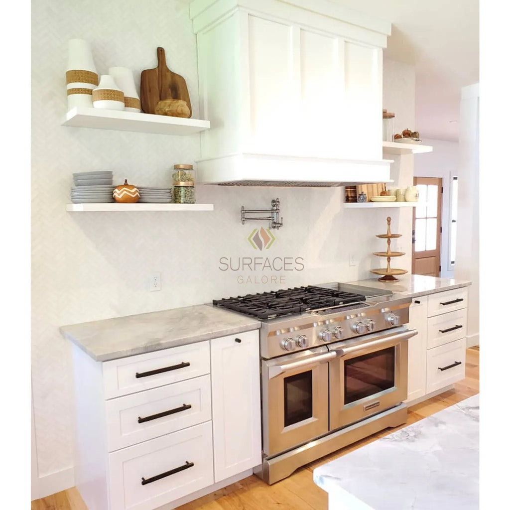 Elegant white kitchen featuring Thassos White marble quarter-round trim with stainless steel range