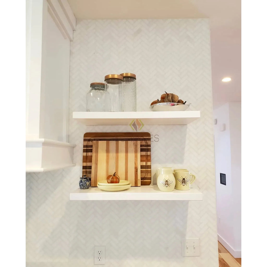 White floating shelves decorated with kitchen items featuring Thassos White Herringbone marble